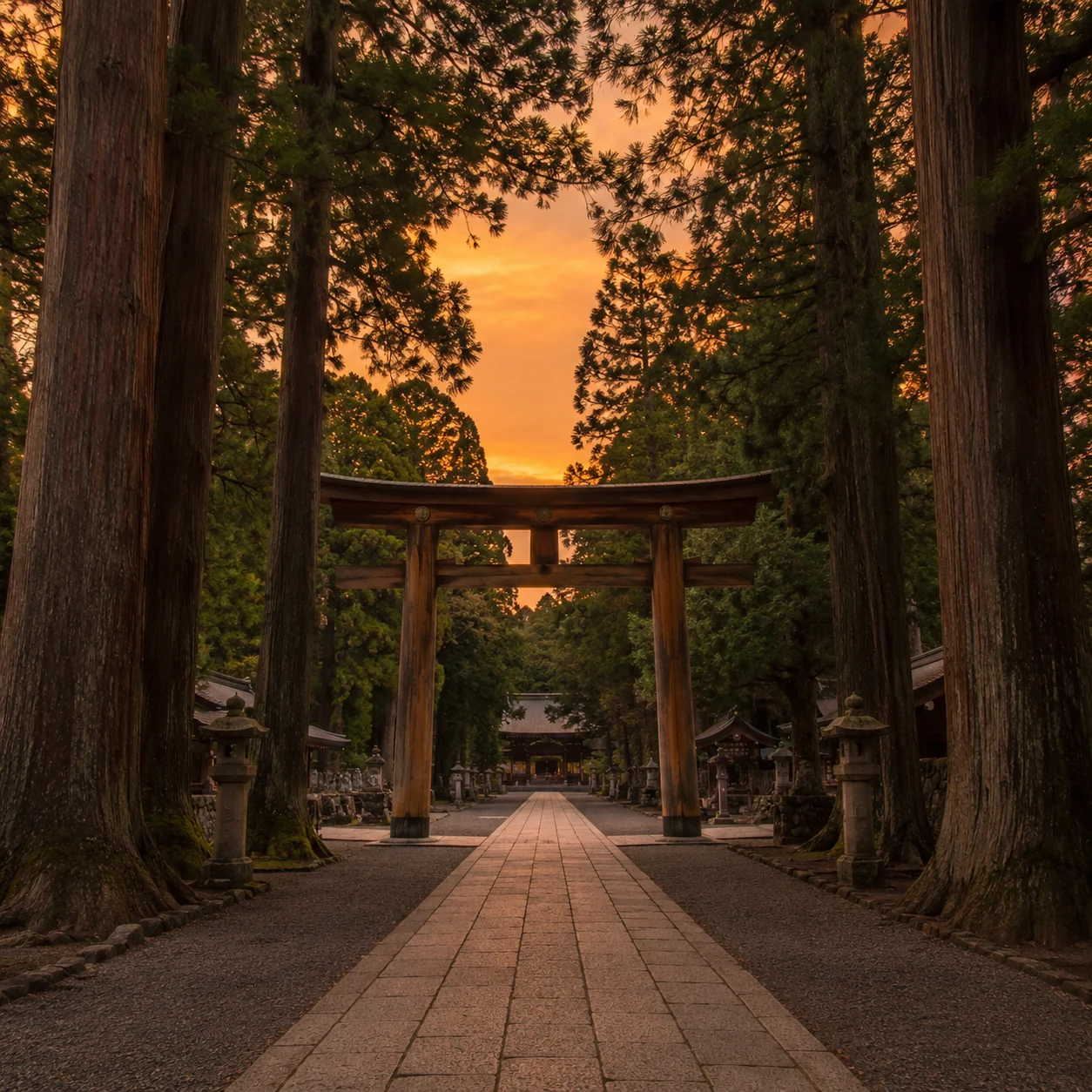 夕暮れの空を背に立つ神社の鳥居と、その手前に伸びる石畳の参道